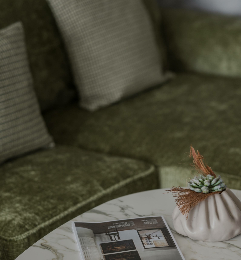 Sitzbereich mit Tisch im Wellnesshotel Naturns Ein grünes Sofa und ein Marmortisch mit Dekoration in einem ruhigen Sitzbereich.